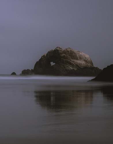 ocean rock formation under gray sky sea